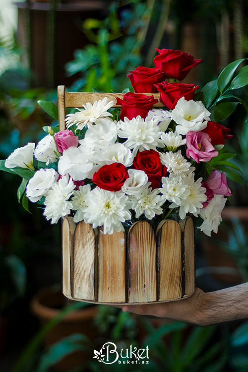 Composition in a wooden basket with roses and chrysanthemums